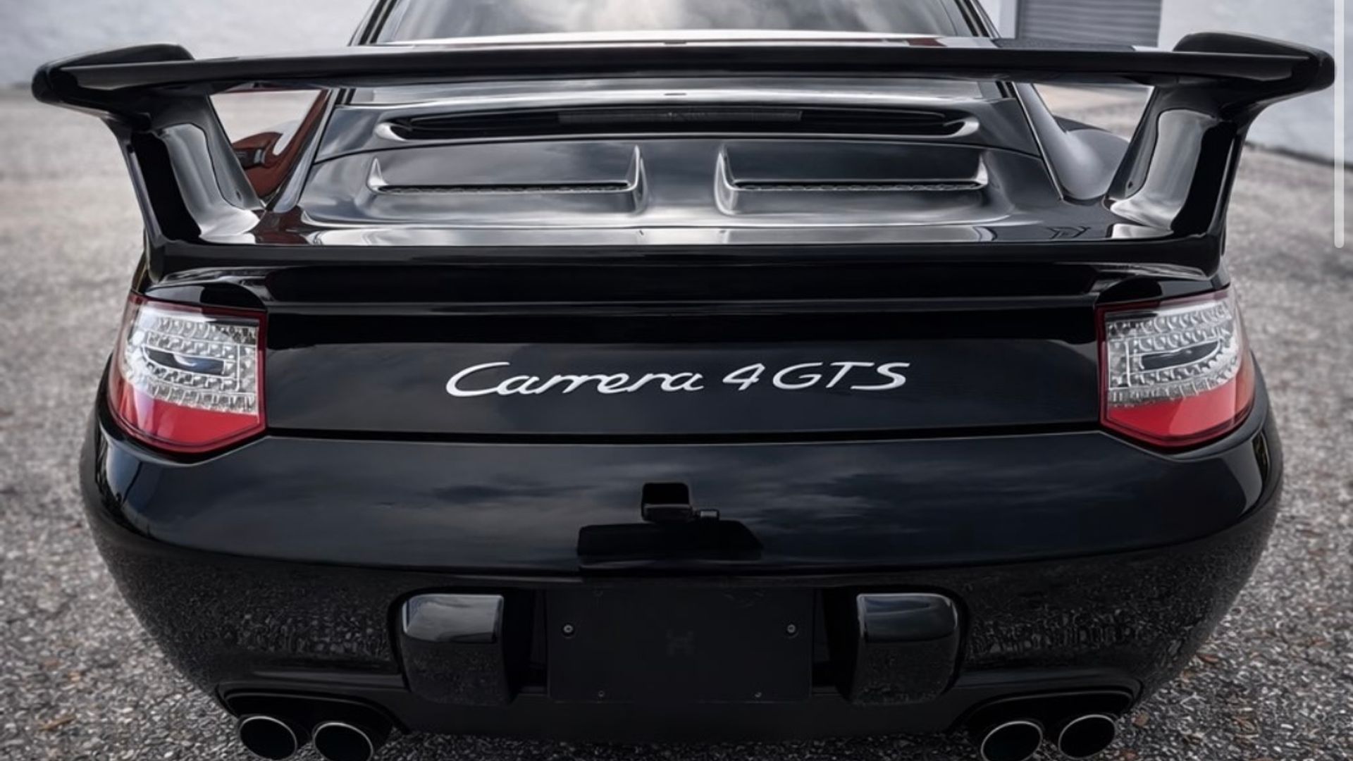 Rear of a black Porsche 911 Carrera 4 GTS with the rear wing raised