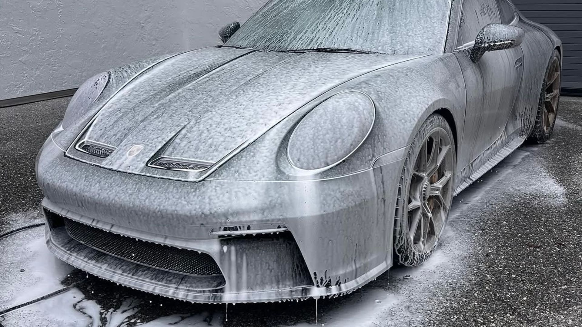 A Porsche 911 covered in snow foam during the pre-wash